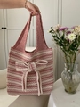 Detail der rosa-weißen Stricktasche mit großer dekorativer Schleife und Wellenmuster-Optik - Rosa