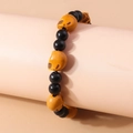 Halloween beaded bracelet with black shiny beads and orange carved skull charms - Skull Style / Brown