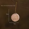 Pallina di Natale in vetro rosa con trama a rilievo appesa a un ramo decorativo - Rosa Ciliegio Rotondo
