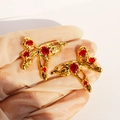 Golden liquid metal butterfly stud earrings with red zircon stones on a white background - Red Zirconia