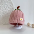 Detailansicht der rosa Strickmütze für Babys mit grünem Blatt und kleinem 'Baby' Etikett - Rosa
