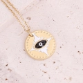Detail of gold evil eye pendant with enamel accents on textured stone surface - Black