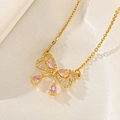 Détail macro du collier nœud doré avec gemme rose en poire sur soie blanche - Nœud Gemme Rose (F411)