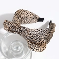 Close-up of leopard print headband with a large bow on a transparent glass display - Small Leopard Orange