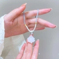 Detail of white lotus flower pendant on light blue braided cord held by hand - White Lotus Pendant Necklace (11279)
