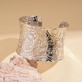 Nahaufnahme der breiten silberfarbenen Armspange mit aufwendiger Paisley-Blumenprägung - Silber
