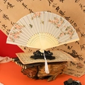 Classic Chinese folding fan with pink floral patterns, bamboo ribs and white tassel on a stand - Peach Garden
