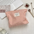 Detail of pink and yellow striped cosmetic bag featuring a woven label and zipper closure - Pink Yellow