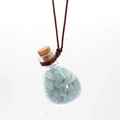 Detail of a glass pendant filled with light blue crushed crystals and a cork stopper - Aquamarine