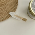 Dettaglio di un fermaglio per capelli bianco a griglia su vassoio in legno con candela - Sirena Argyle