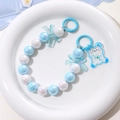 Detalle de colgante de cuentas con lazo azul y oso en una bandeja redonda blanca - Degradado Azul Blanco-Oso