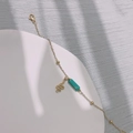 Detail eines Goldarmbands mit türkisfarbener Perle und Schlangenanhänger auf dem Display - Schlange