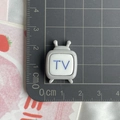Gros plan d'un accessoire télé rétro en résine 2x2cm gris avec inscription TV bleue - Télévision