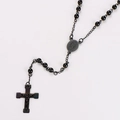 Dettaglio di un rosario nero con crocifisso di Gesù e medaglia di Maria su sfondo bianco - Nero