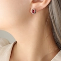 Oval red zircon stud earrings with silver titanium steel finish on model's ear - Steel Red Zirconia