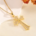 Detail einer goldenen Kreuzkette mit funkelndem Zirkon auf rustikalem Hintergrunddekor - Schmale 3-Punkte-Halskette / Gold