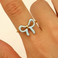 Close-up of golden stainless steel ring with light blue enamel bow on a finger - Light Blue Enamel Bow Style (6915)