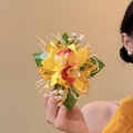 Elegant yellow gradient fabric orchid hair clip with green leaves held by a model - Duckbill Hair Clips / Yellow