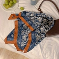 Blaues Seidentuch mit Paisley-Muster und orangefarbenem Rand an einer Lederhandtasche - Blau und Orange Paisley