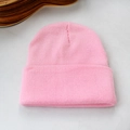 Détail de la texture et du revers d'un bonnet en maille rose sur fond gris clair - Rose