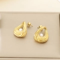 Close-up of golden teardrop earrings with hollow texture and pearl inlay on a jewelry box - Hollow Teardrop Style (KE115915-GC)