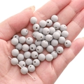 Macro shot of gray matte acrylic round beads held in hand for DIY jewelry making - Crescent Grey