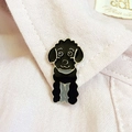 Broche caniche noir en émail et alliage de zinc sur le col d'une chemise rose - Style Caniche Noir