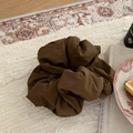 Brown fabric scrunchie on vintage rugs with books and decor in a flat lay view - Brown