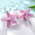 Macro detail of two pink resin starfish ornaments with white spots on a white plate - Small / Pink Purple