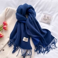 Close-up of a soft blue cashmere-style scarf with fringe on a white textured coat - Navy Blue