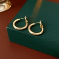Detailed view of minimalist gold circular hoop earrings on a textured green gift box - 20mm / Gold