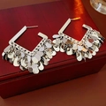Detailed close-up of silver square tassel drop earrings on a vintage red wood box - Silver