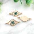 Makroaufnahme von goldenen Evil Eye Schmuckverbindern mit blauen Steinen auf Marmor - KC Gold Böser Blick-14577