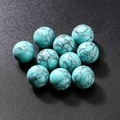 Spherical turquoise beads with black spiderweb patterns on dark background - Turquoise Colored Stone