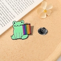 Cute cartoon green frog enamel pin holding a rainbow flag on a warm textured surface - Alloy / Frog Leaning on Rainbow