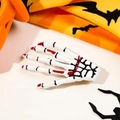 Close-up of Halloween skeleton hand hair clip with red accents on a pumpkin background - White with Blood