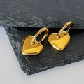 Primo piano dettagliato degli orecchini a cuore placcati oro 18k su fondo in pietra - Oro