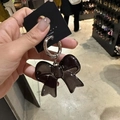 Llavero de lazo acrílico marrón translúcido con anillo de metal plateado en la mano - Lazo Negro Translúcido