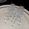 Dettaglio di orecchini a nappa con cristalli a goccia su un piatto di ceramica bianca - Perno per orecchini in argento - Stile cristallo argento