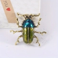 Vintage gold beetle brooch with blue-green enamel finish on a white textured background - Gradient Blue Green Beetle