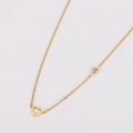 Primer plano detallado del collar de acero dorado con corazón hueco y cristal incrustado - Dorado