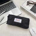 Detail of black pleated fabric stationery pouch with tulip floral label on office desk - Black
