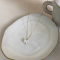 Détail d'un collier en perles dorées avec pendentif Mickey sur un plateau en céramique - Or 14K Perle Artificielle Forme de Souris
