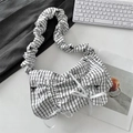 Detailed view of checkered pleated handbag with black bow embroidery on a desk - Black Grid Black Bow