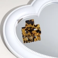 Close-up of leopard pattern hair claw clip on heart-shaped pearl mirror with reflection - Yellow Leopard Print