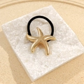 Chic golden starfish hair tie with high-elastic black rope on marble display stand - Starfish Hair Tie