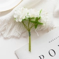 Small bouquet of white artificial silk flowers with green leaves on a soft knit blanket - Cream