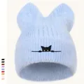 Detailstruktur der hellblauen Strickmütze mit Katzenohren und Stickerei-Augen - Hellblau