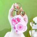 Pink bear camera keychain toy with gold bell and metal ring shown in hand - Camera Game Console - Pink