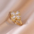 Golden rotating four-leaf clover ring with zircon stones on pink satin backdrop - Four Leaf Ring / Gold